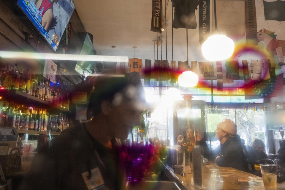 With a rainbow mustache drawn on a porthole door connecting the kitchen and bar, patrons watch a beach volleyball match on big-screen TV at The Sports Bra sports bar in Portland, Ore., April 24, 2024. (AP Photo/Jenny Kane)