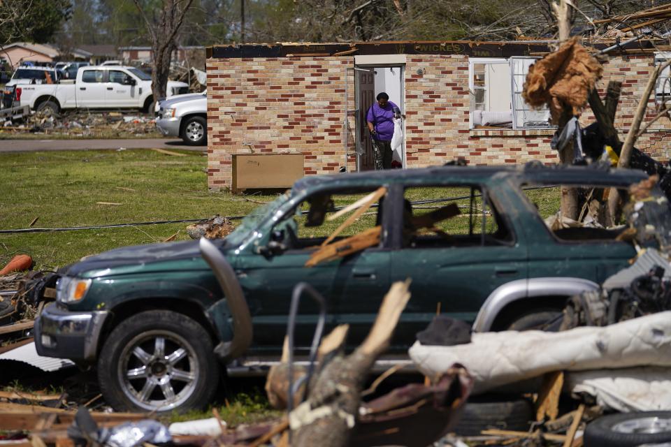 FILE - A woman collects belongings near a damaged home, March 26, 2023, in Rolling Fork, Miss. While the dangers of tornadoes to mobile homes have long been known, and there are ways to mitigate the risk, the percentage of total tornado deaths that happen in mobile homes has been increasing. (AP Photo/Julio Cortez, File)