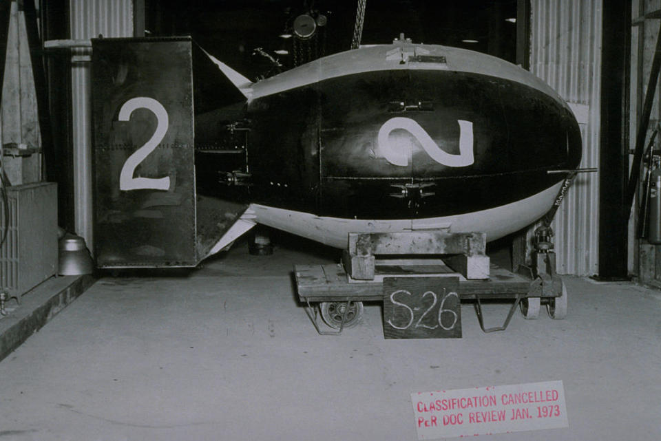 Large bomb with the number 2 painted on it, displayed in a hangar. Red sign reads: "CLASSIFICATION CANCELLED Per DOC REVIEW JAN 1973"