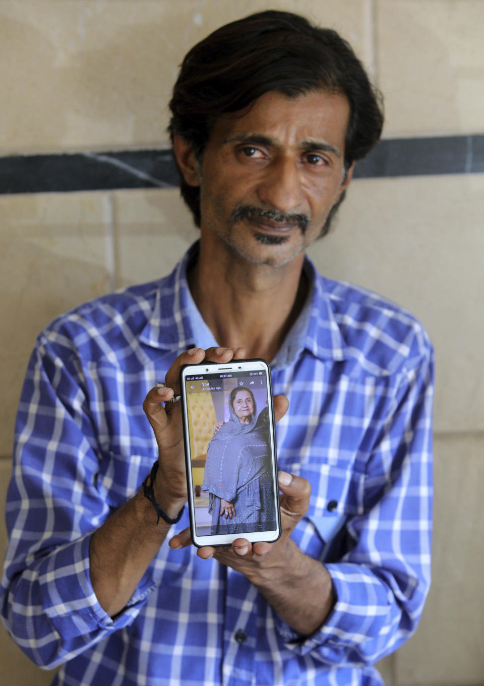 Pakistani Shahid Ahmed shows the picture of his mother Irshad Begum, who was killed in the Friday's plane crash, on his mobile phone outside a morgue in Karachi, Pakistan, Saturday, May 23, 2020. An aviation official says a passenger plane belonging to state-run Pakistan International Airlines carrying passengers and crew has crashed near the southern port city of Karachi. (AP Photo/Fareed Khan)