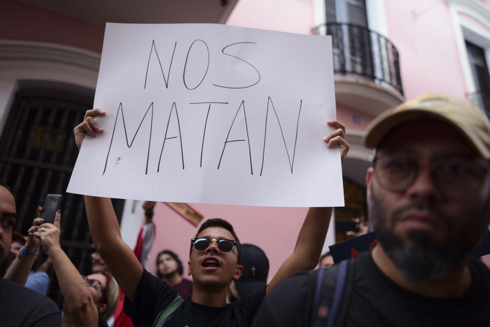 A young man holds a sign that reads in Spanish "They are killing us" while protesting outside the executive mansion known has La Fortaleza, in Old San Juan, demanding the resignation of Governor Wanda Vazquez after the discovery of an old warehouse filled with unused emergency supplies in San Juan, Puerto Rico, Monday, Jan. 20, 2020. Anger erupted on Saturday after an online blogger posted a live video of the warehouse in the southern coastal city of Ponce filled with water bottles, cots, baby food and other basic supplies that had apparently been sitting there since Hurricane Maria battered the U.S. territory in September 2017. (AP Photo/Carlos Giusti)