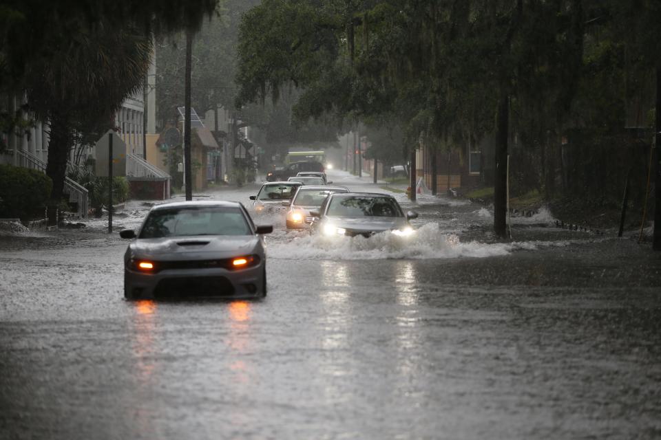 Vehicles attempt go around a car that is stuck on flood waters on Whitaker Street near 34th Street as rain continues to fall on Monday, July 22, 2024.