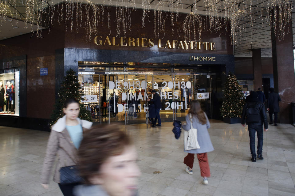 Pedestrians walk in front of the Galeries Lafayette department store in Paris, Thursday, Dec.19, 2019. French retailers, hotels and cafes are struggling at the height of the holiday shopping season, because a protracted transportation strike and repeated protests in Paris and other cities are keeping shoppers and visitors away. And it's the second year in a row _ last year's Christmas season was hit by yellow vest protests. (AP Photo/Thibault Camus)