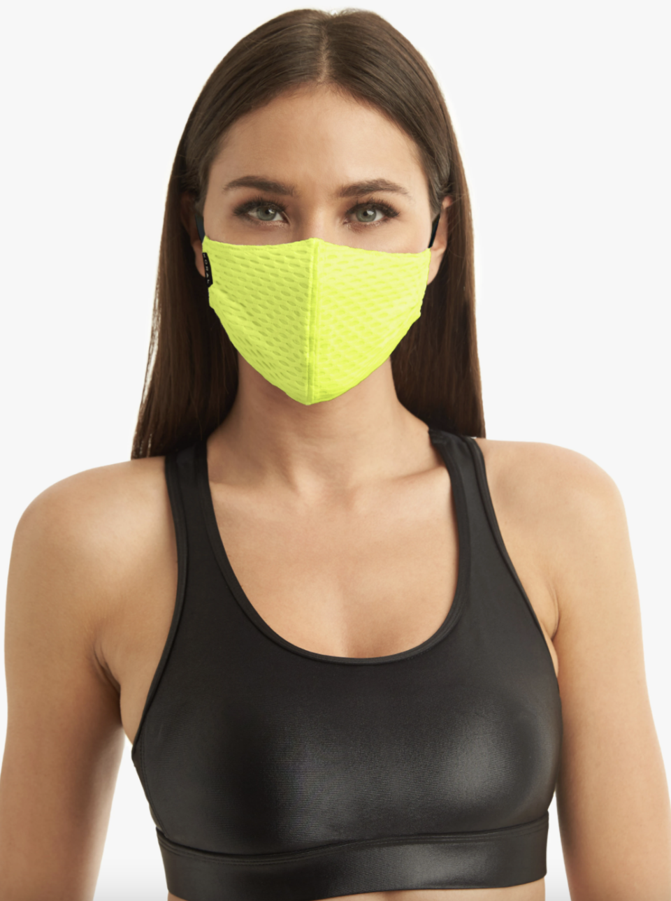 brunette woman wearing black sports bra and neon lime face mask