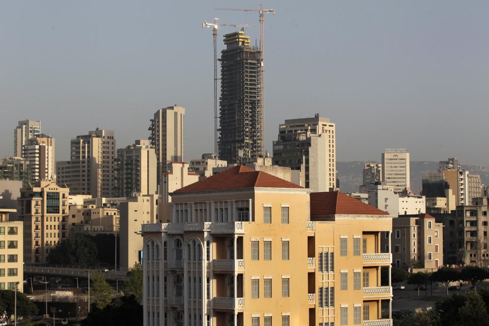 In this April 8, 2014 photo, an old building with a traditional red brick roof, foreground, is overshadowed by newer, taller modern buildings, some still under construction, in Beirut, Lebanon. One by one, the old traditional houses of Beirut are vanishing as luxury towers sprout up on every corner, altering the city's skyline almost beyond recognition amid an ongoing construction frenzy seemingly immune to tensions from the civil war raging next door. (AP Photo/Hussein Malla)