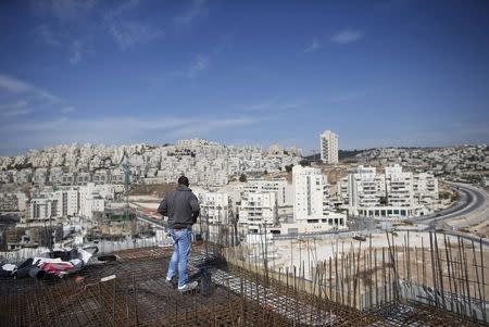 A labourer stands on an apartment building under construction in a Jewish settlement known to Israelis as Har Homa and to Palestinians as Jabal Abu Ghneim, in an area of the West Bank that Israel captured in a 1967 war and annexed to the city of Jerusalem, in this October 28, 2014 file photo. REUTERS/Ronen Zvulun/Files