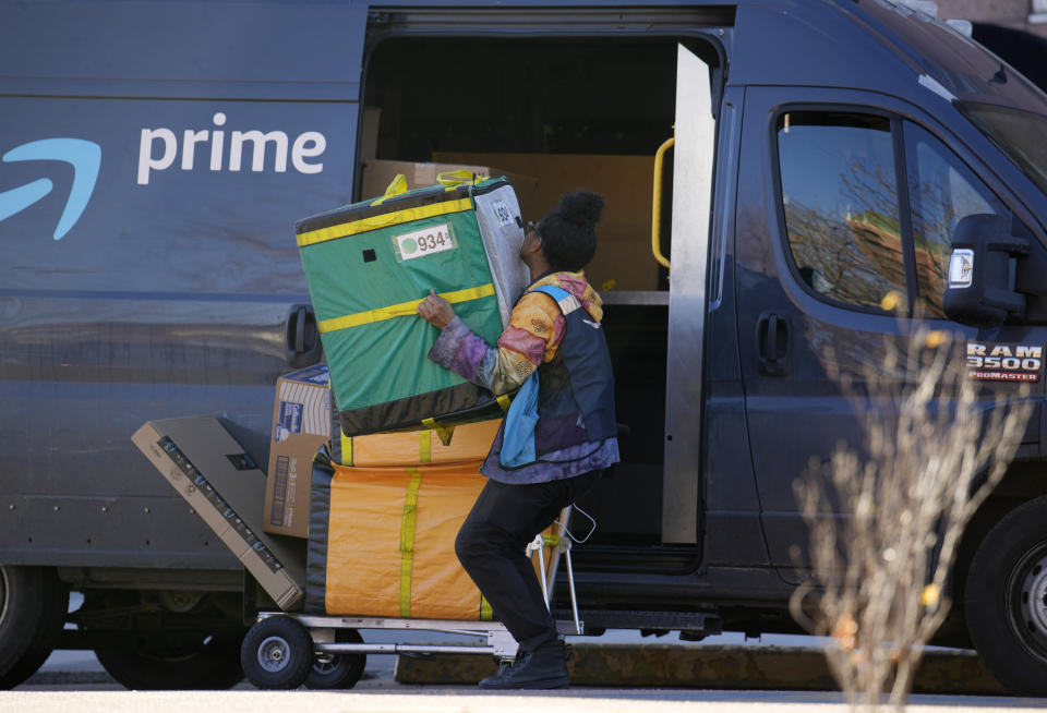 An Amazon Prime delivery person lifts packages while making a stop at an apartment building on Tuesday, Nov. 28, 2023, in Denver. Walmart, Target and Amazon are all-in on the shipping wars, a move retail experts say will help them maintain a competitive edge against low-cost Chinese retailers Shein and Temu. (AP Photo/David Zalubowski)