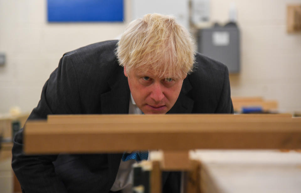 Prime Minister Boris Johnson looks at a piece of wood in a vice during a visit to Exeter College. The visit comes ahead of a speech in which he is expected to announce guaranteed opportunities for life-long learning to help create a jobs recovery after the pandemic.