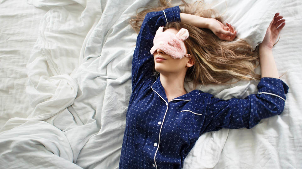 Cute blonde in her bed in blue pajamas and sleep mask, top view - Image.