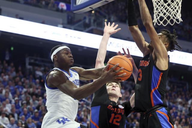 Kentucky's Oscar Tshiebwe (34) shoots while defended by Florida's Colin Castleton (12) and Alex Fudge (3) during the first half of an NCAA college basketball game in Lexington, Ky., Saturday, Feb. 4, 2023. (AP Photo/James Crisp)