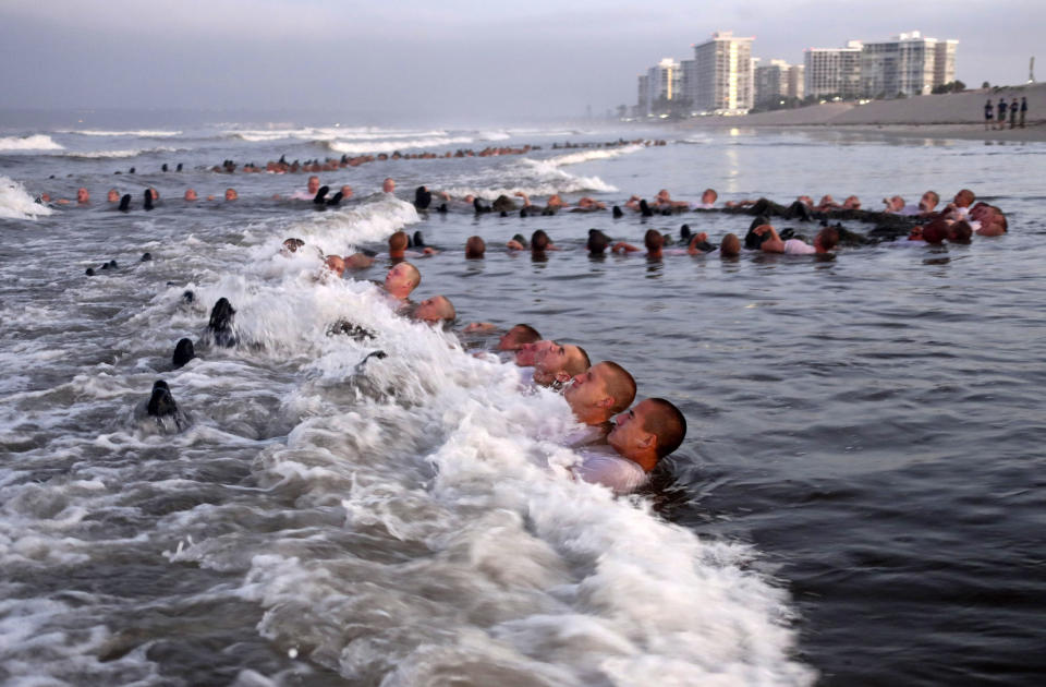 This Monday May 4, 2020, photo provided by the U.S. Navy shows SEAL candidates participating in "surf immersion" during Basic Underwater Demolition/SEAL (BUD/S) training at the Naval Special Warfare (NSW) Center in Coronado, Calif. Navy SEAL recruits and their instructors are being tested for the coronavirus as the candidates in one of the military's most grueling programs return to training with new social distancing guidelines, a top official said Tuesday, May 5, 2020. (MC1 Anthony Walker/U.S. Navy via AP)