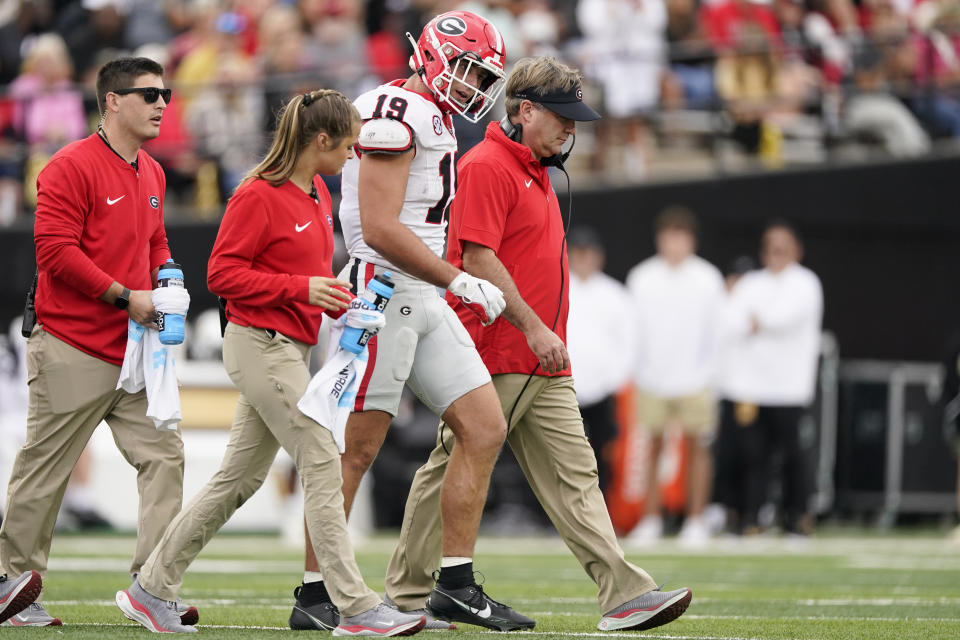 Georgia tight end Brock Bowers (19) walks of the field with head coach Kirby Smart, right, after being injured in the first half of an NCAA college football game against Vanderbilt, Saturday, Oct. 14, 2023, in Nashville, Tenn. (AP Photo/George Walker IV)