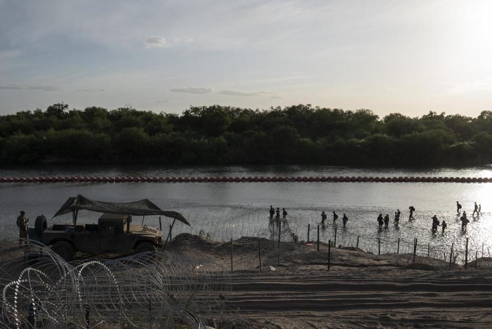 Migrants walk along the Rio Grande passed the recently installed buoys in Eagle Pass, Texas on July 29, 2023. As there is concertina wire installed along the Urbina’s property, migrants are told to walk to the end of the property. Many make that walk which can be difficult to do through slippery rocks in the water, the current and the inclined river bank, while some find spots through the concertina wire and manage to get through.
Verónica G. Cárdenas for The Texas Tribune