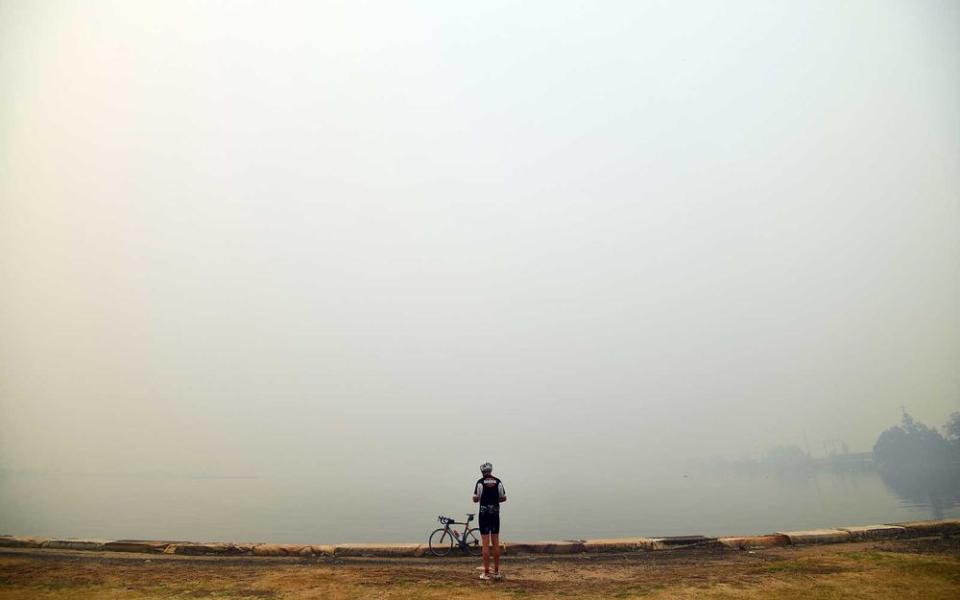 A cyclist takes pictures of thick toxic smoke from bushfires cutting through inland forests, in Gosford north of Sydney on December 10, 2019. | SAEED KHAN/Getty Images