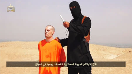 A masked Islamic State militant holding a knife speaks next to man purported to be U.S. journalist James Foley at an unknown location in this still image from an undated video posted on a social media website. REUTERS/Social Media Website via REUTERS TV