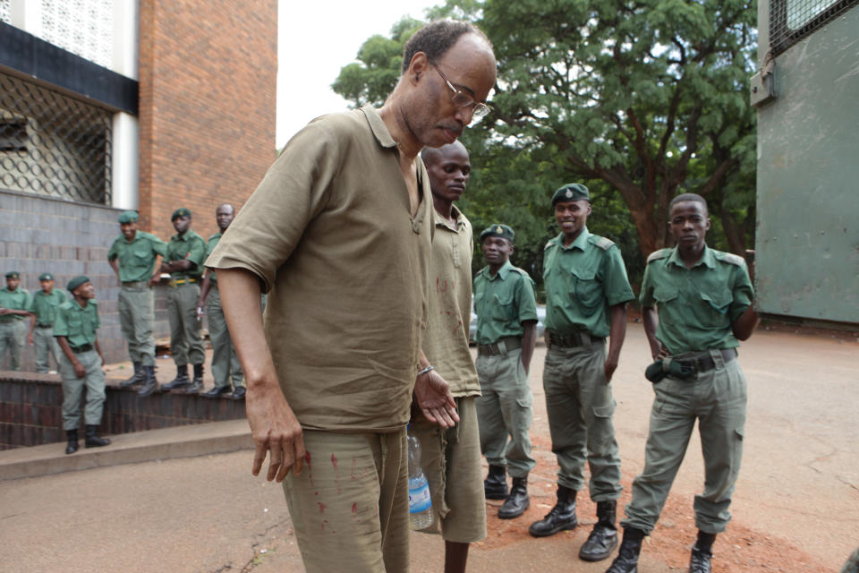 Former US Congressman Mel Reynolds, centre left, prepares to enter a prison truck while handcuffed following his court appearance at the magistrates courts in Harare, Thursday, February, 20, 2014. Reynolds was arrested in Zimbabwe for allegedly possessing pornographic material and violating immigration laws. (AP Photo/Tsvangirayi Mukwazhi)