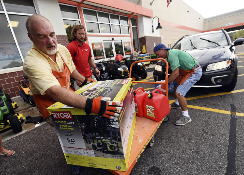 Jim Craig, David Burke and Chris Rayner load generators as people buy supplies at The Home Depot in Wilmington, North Carolina on Monday.