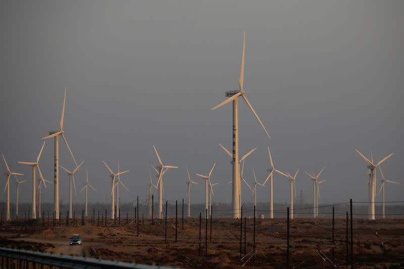 FILE PHOTO: A car drives near wind turbines on a power station near Yumen