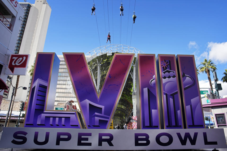 Un grupo de personas hacen descenso por cables de acero encima del logo del Super Bowl 58, el viernes 2 de febrero de 2024, en Las Vegas. (AP Foto/John Locher)