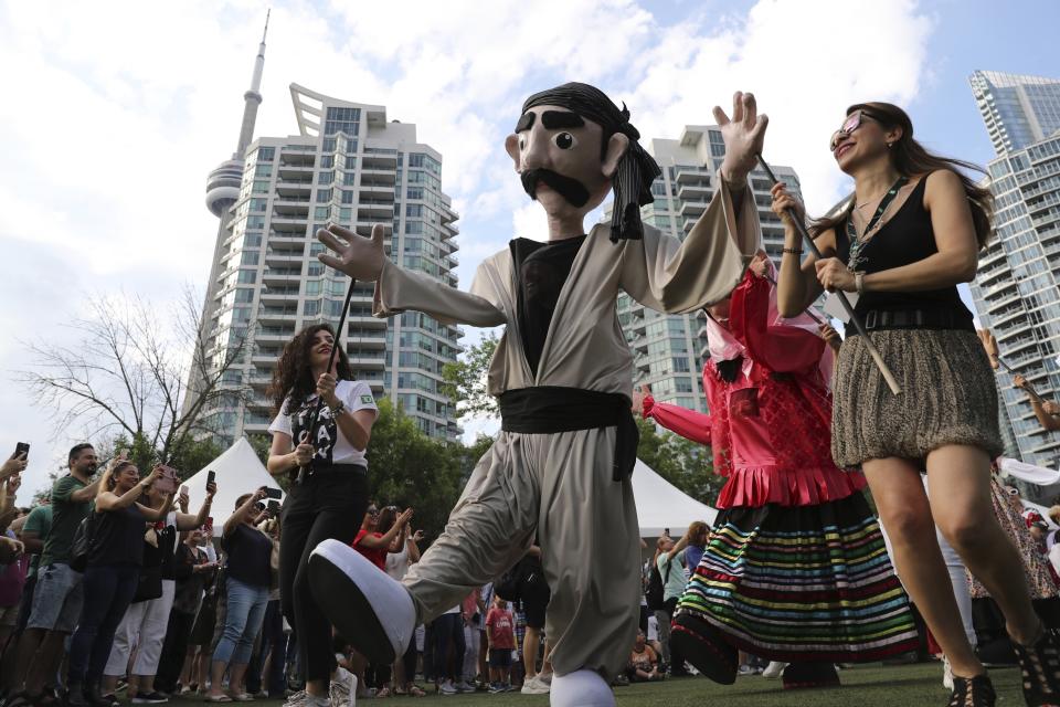 In this Saturday, July 27, 2019 photo, people take photos of the puppets from Iran's Kurdistan and Gilan provinces, showcasing the theme of this year's festival "UNITY" during the Tirgan summer festival at the Harbourfront Centre in Toronto, Canada. The event aims to preserve and celebrate Iranian and Persian culture, said festival CEO Mehrdad Ariannejad. Among those who attended were second-and third-generation immigrants, many of whom have never been to Iran or have not been there since leaving the country following the 1979 Islamic Revolution. (AP Photo/Kamran Jebreili)