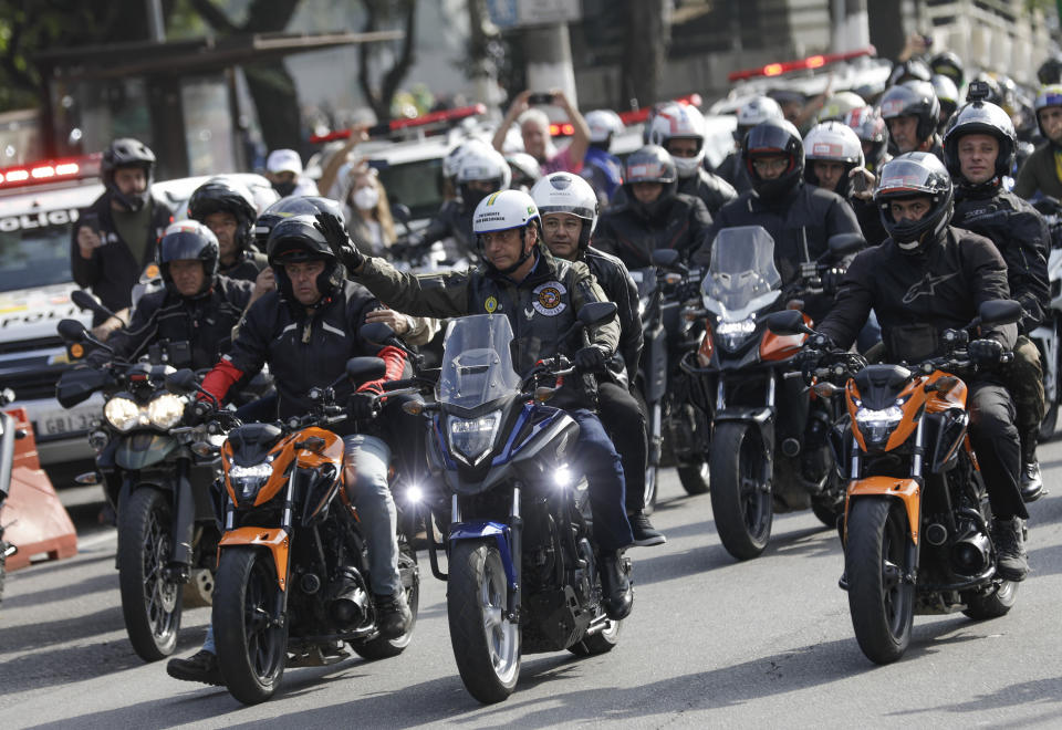 Brazil's President Jair Bolsonaro, center, waves as he leads a caravan of motorcycle enthusiasts following him through the streets of the city, in a show of support for Bolsonaro, in Sao Paulo, Brazil, Saturday, June 12, 2021. (AP Photo/Marcelo Chello)