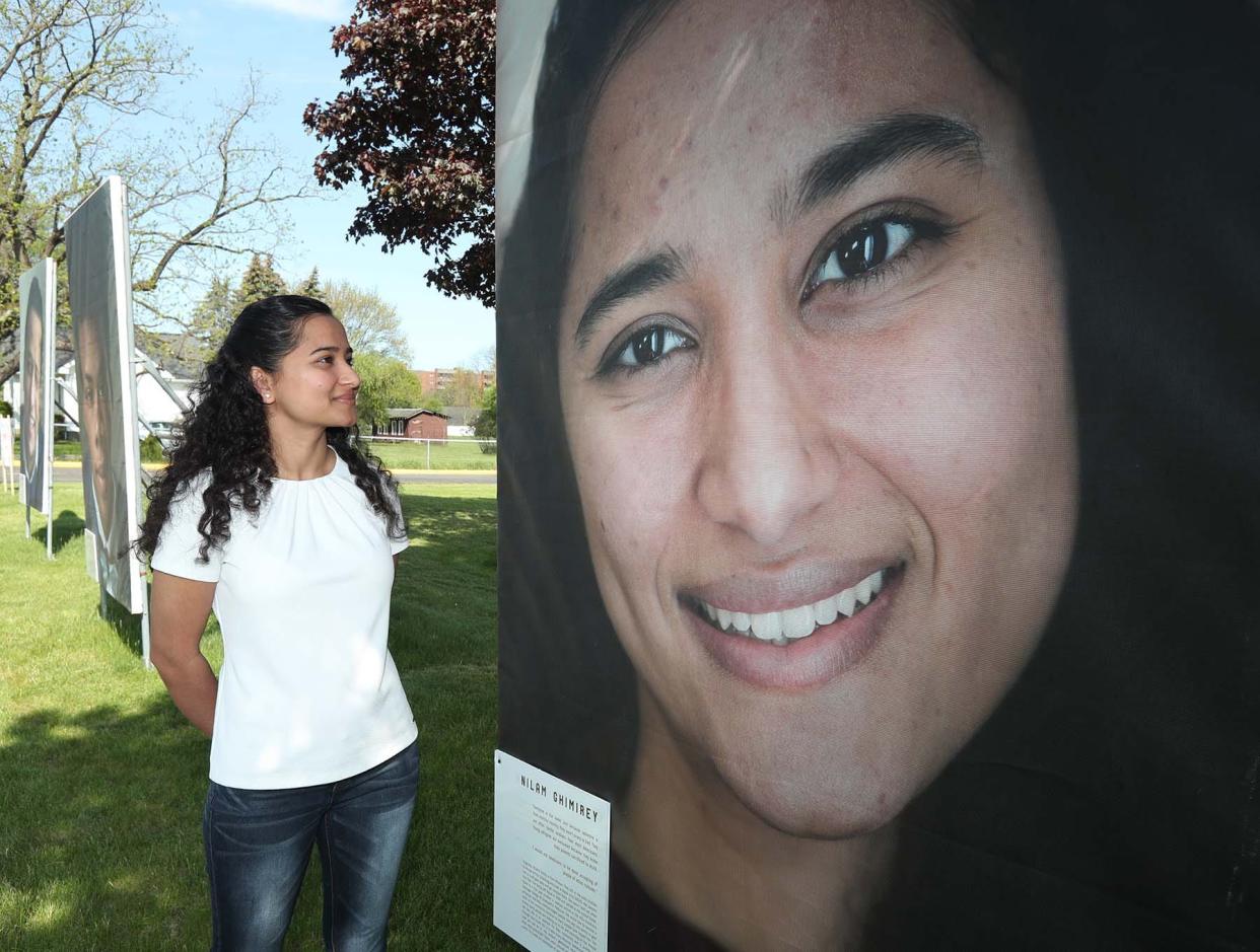 Nilam Ghimirey stands next to portrait taken by photographer Erin LaBelle that is part of the “We the People” exhibit on display at Stow-Munroe Falls High School on Friday.