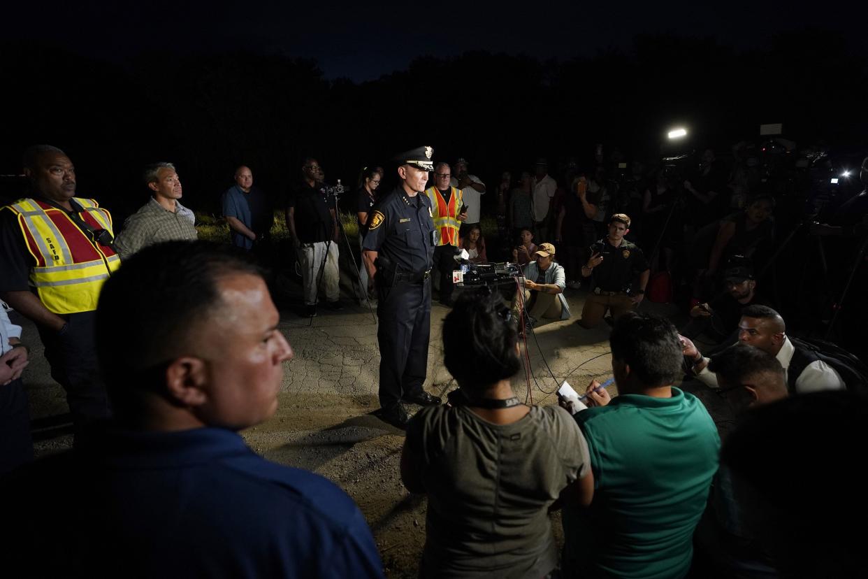 San Antonio Police Chief William McManus, center, briefs media and others at the scene where dozens of people have been found dead and multiple others were taken to hospitals with heat-related illnesses after a semitrailer containing suspected migrants was found on Monday, June 27, 2022, in San Antonio.