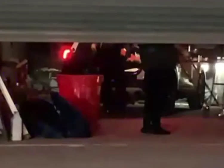 警方將裝置屍體的橘色塑膠筒，搬運上警車。讀者提供