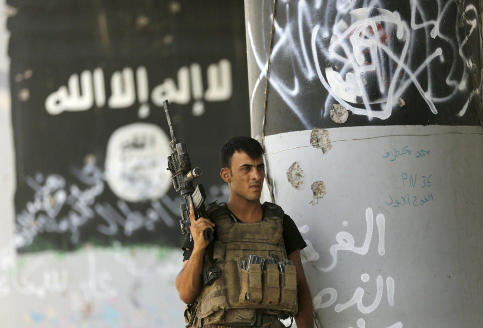 FILE - In this June 27, 2016, file photo, a member of Iraqi counterterrorism forces stands guard near Islamic State group militant graffiti in Fallujah, Iraq. (AP Photo/Hadi Mizban, File)