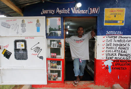 A former child soldier who received the Journey Against Violence (JAV) Program poses for a picture in front of his business center in Mabaclay, Liberia, July 3, 2016. REUTERS/Thierry Gouegnon