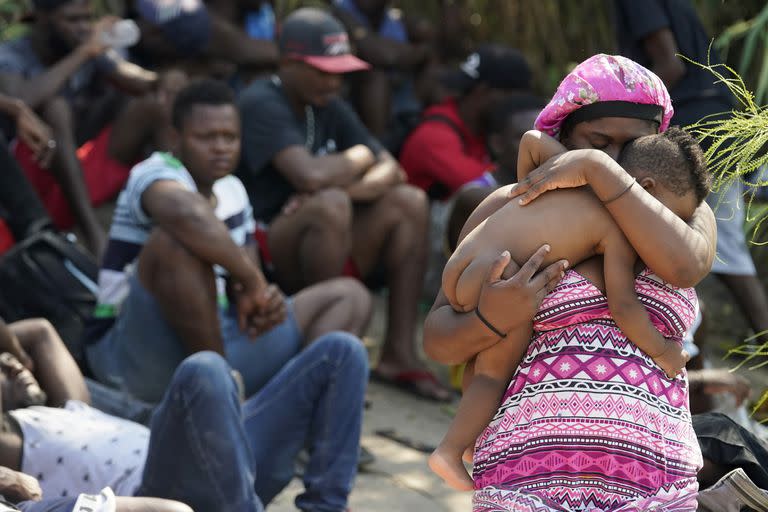 Una migrante alza a su bebé mientras espera a que otros crucen el Río Grande