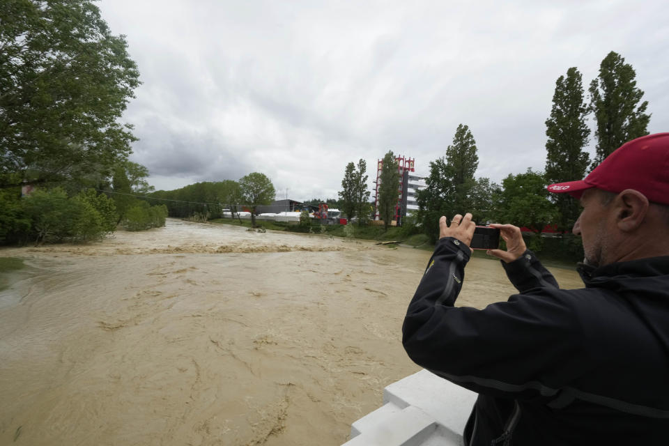 A man photographs the swollen Santerno River with behind the Enzo e Dino Ferrari circuit, in Imola, Italy, Wednesday, May 17, 2023. The weekend's Emilia-Romagna Grand Prix in Imola has been canceled because of deadly floods. Formula One said it made the decision for safety reasons and to avoid any extra burden on the emergency services. F1 personnel had earlier been told to stay away from the track after floods affected large parts of the Emilia-Romagna region. (AP Photo/Luca Bruno)