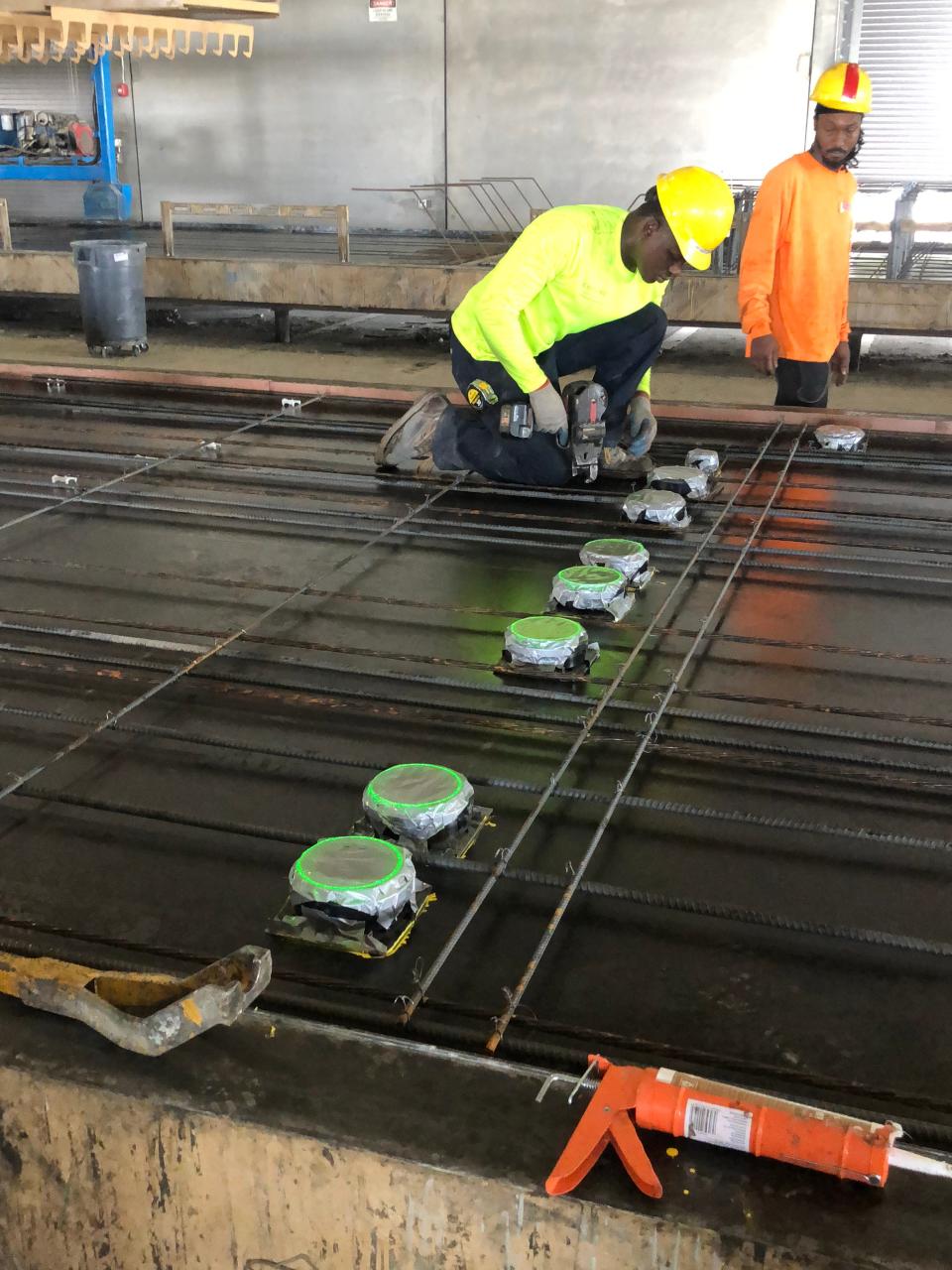 Construction workers installing rebar using robotic-mounted lasers for installation precision.