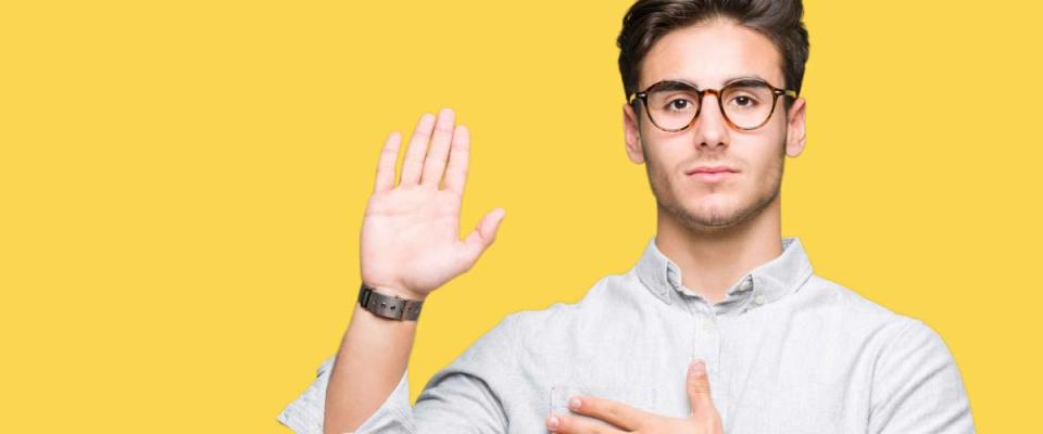 Young handsome man wearing glasses over isolated background Swearing with hand on chest and open palm, making a loyalty promise oath