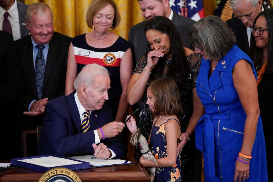 President Joe Biden gives the pen he used to sign the "PACT Act of 2022" to Brielle Robinson, daughter of Sgt. 1st Class Heath Robinson, who died of cancer two years ago, during a ceremony in the East Room of the White House, Wednesday, Aug. 10, 2022, in Washington.