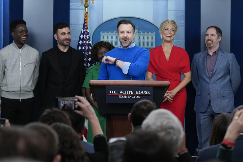 Jason Sudeikis, fourth from left, who plays the title character in the Apple TV+ series “Ted Lasso”, speaks as he joins White House press secretary Karine Jean-Pierre, third from left, and fellow cast members, from left, Toheeb Jimoh, Brett Goldstein, Hannah Waddingham, and Brendan Hunt, during the daily press briefing at the White House in Washington, Monday, March 20, 2023. (AP Photo/Susan Walsh)