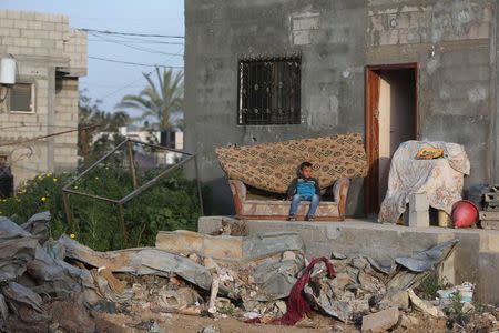 A Palestinian boy sits on a sofa outside his family's house, that witnesses said was damaged by Israeli shelling during a 50-day war last summer, in Khan Younis in the southern Gaza Strip, March 10, 2015. REUTERS/Ibraheem Abu Mustafa