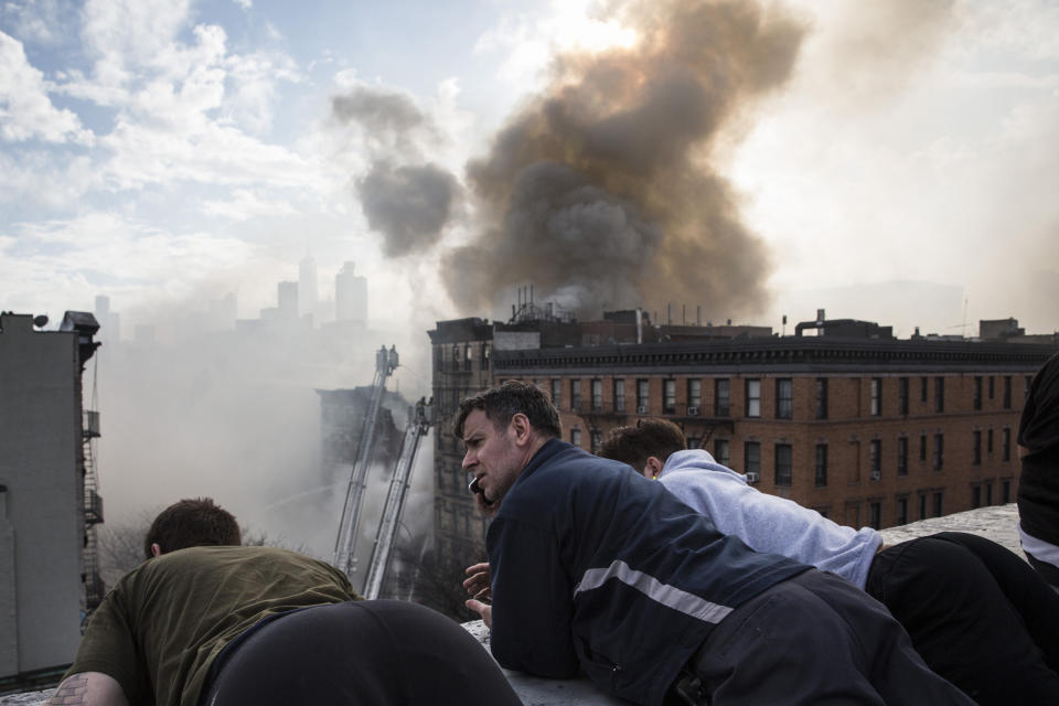 NEW YORK, NY - MARCH 26:  Local residents watch as New York City Fire Department personel work to extinguish a fire as a building burns after an explosion on 2nd Avenue of Manhatten's East Village on March 26, 2015 in New York City. Officials have reported that at least 12 people were injured but it is unclear if anyone was trapped inside either building.  (Photo by Andrew Burton/Getty Images)