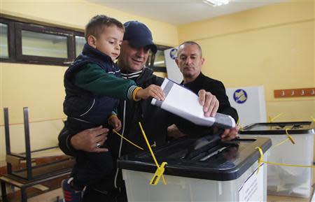 A Kosovo Albanian man places his ballot paper into a voting box at the polling station in the southern part of the divided town of Mitrovica in Kosovo, November 3, 2013. REUTERS/Hazir Reka