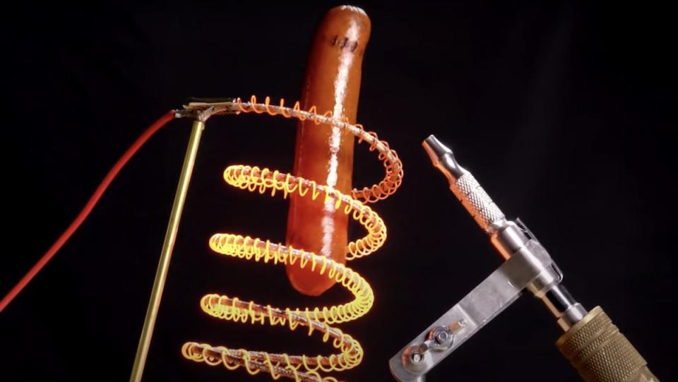 A floating hot dog surrounded by glowing red hot metal coils and an air gun