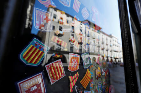 Badges bearing regional flags are sen behind a window reflecting a square in Girona, Spain, October 7, 2017 REUTERS/Rafael Marchante