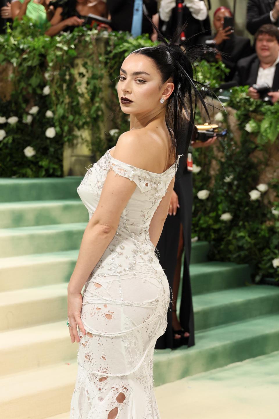 Woman in an elegant off-shoulder white lace gown with a feathered hair accessory