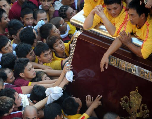 Philippine Catholic pilgrims touch the carriage of the Black Nazarene, a life-size icon of Jesus Christ carrying a cross during the annual religious procession in Manila on January 9, 2012. The "Black Nazarene" march is one of the most spectacular of many religious festivals that feature throughout the year, and police estimated between two and three million people turned up on Monday to be part of the crowd. AFP PHOTO/TED ALJIBE