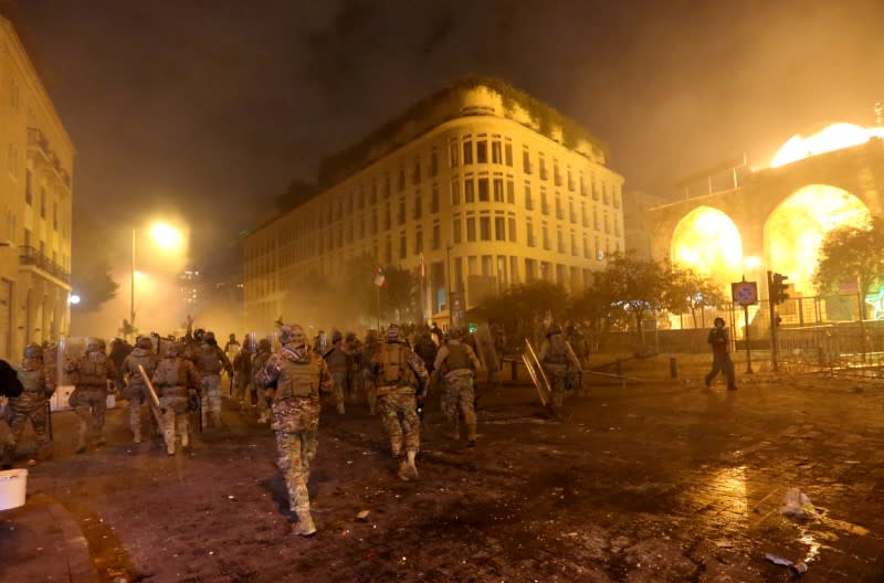 Smoke rises as Lebanese army soldiers walk during a protest against the newly formed government in Beirut