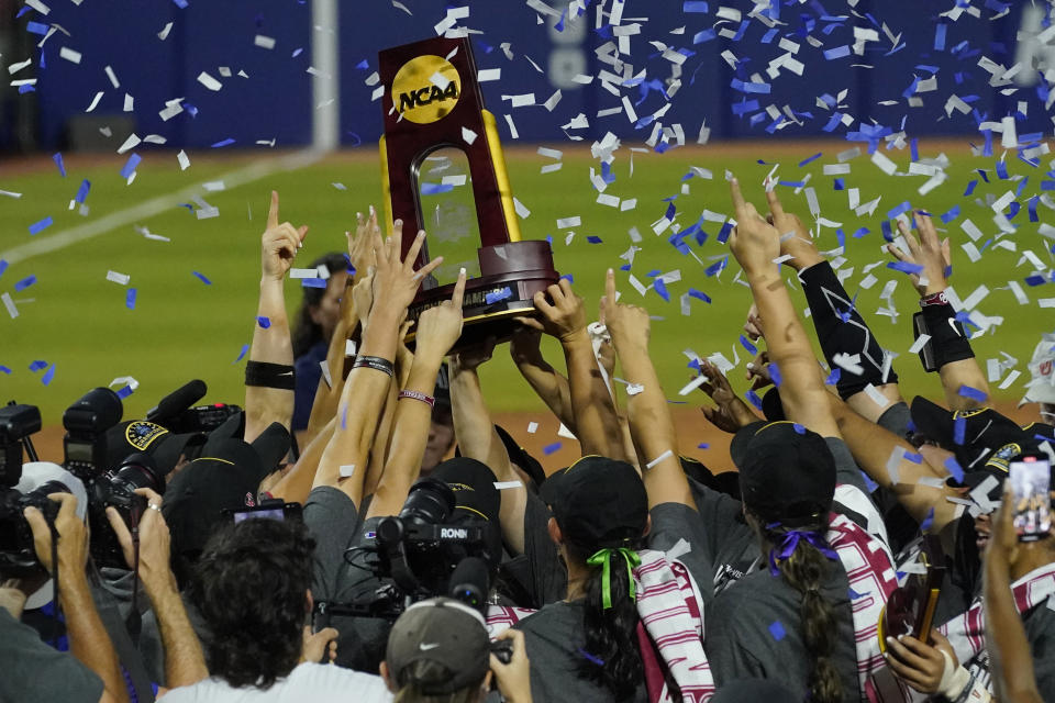 Oklahoma players celebrate with the trophy after defeating Texas in the NCAA Women's College World Series softball finals Thursday, June 9, 2022, in Oklahoma City. (AP Photo/Sue Ogrocki)