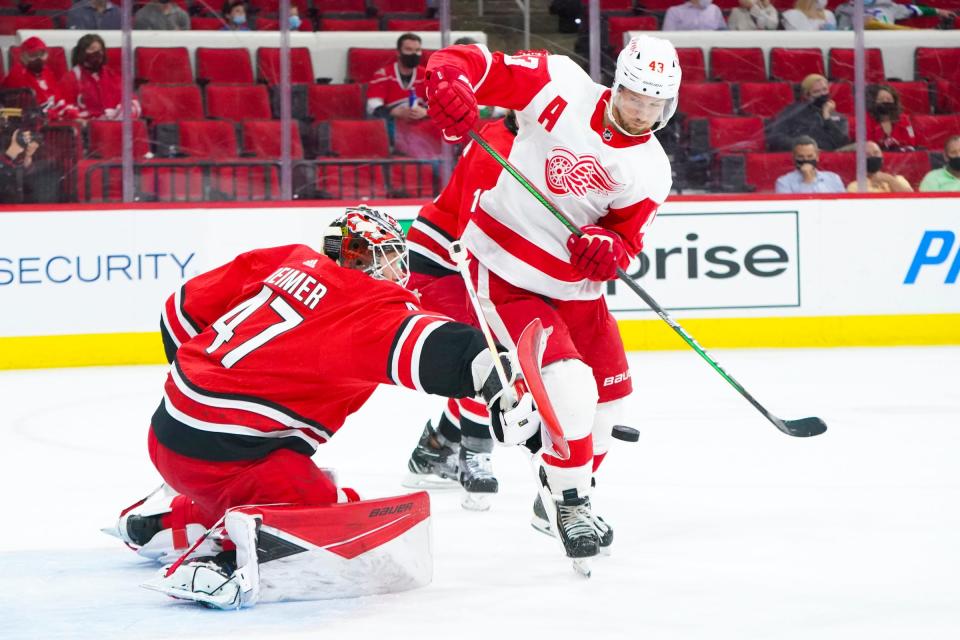 Carolina Hurricanes goaltender James Reimer makes a save in the first period vs. Detroit Red Wings left wing Darren Helm at PNC Arena in Raleigh, N.C., April 29, 2021.
