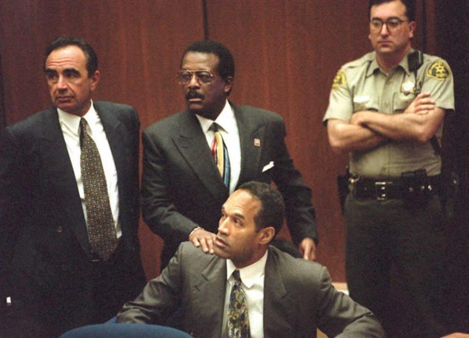 Defense attorney Johnnie Cochran Jr. puts his hand on the shoulder of murder defendant OJ Simpson