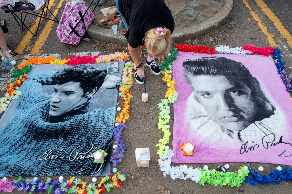 Donna Galloway lights a candle for an Elvis Presley shrine she created on Elvis Presley Boulevard in front of the gates of Graceland prior to the annual Candlelight Vigil to honor Elvis Presley in Memphis, Tenn., on Thursday, August 15, 2024.