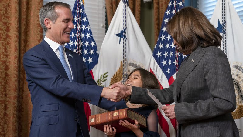 Eric Garcetti, left, next to his daughter Maya Garcetti and holding a heavy and historic Hebrew Bible from the Library of Congress, is sworn in as ambassador to India by Vice President Kamala Harris, Friday, March 24, 2023, in her ceremonial office in the Eisenhower Executive Office Building on the White House complex in Washington.