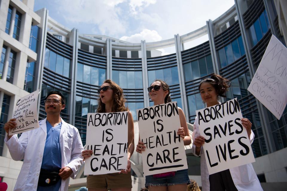 From left, Dr. Kenji Tanaka, Dr. Nina Hill, Dr. Jackie Krevitz and Dr. Ruth Wang hold signs in front of the federal courthouse on Church Street in downtown Nashville on Saturday. The three were part of the "Bans Off Our Bodies" protest, which joined dozens of other rallies like it nationwide.